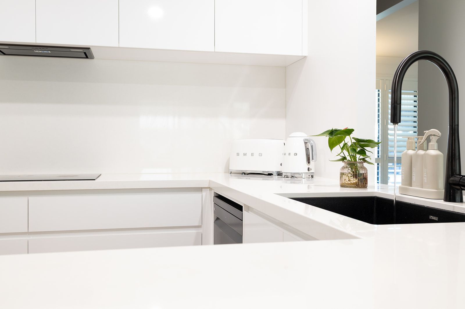 A Modern White Kitchen With a Black Sink and Faucet — Truline Cabinets In Tuchekoi, QLD