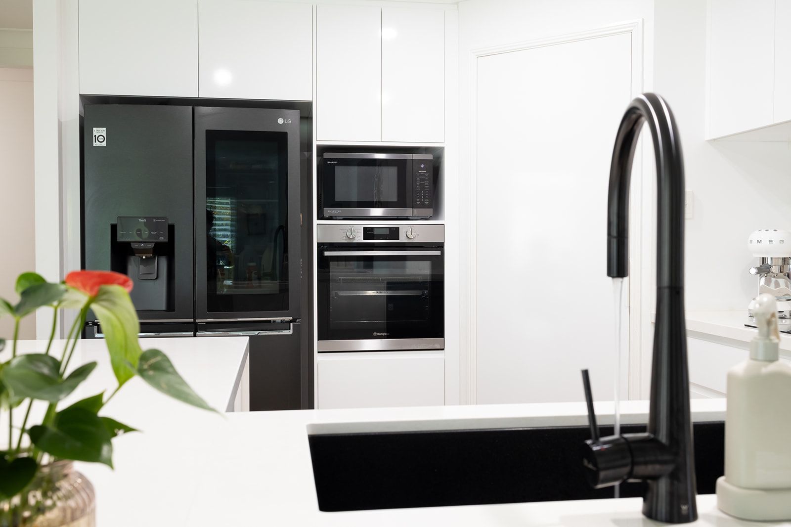 Modern Kitchen With Black Faucet, White Countertops and Cabinets, and Stainless Steel Appliances — Truline Cabinets In Tuchekoi, QLD