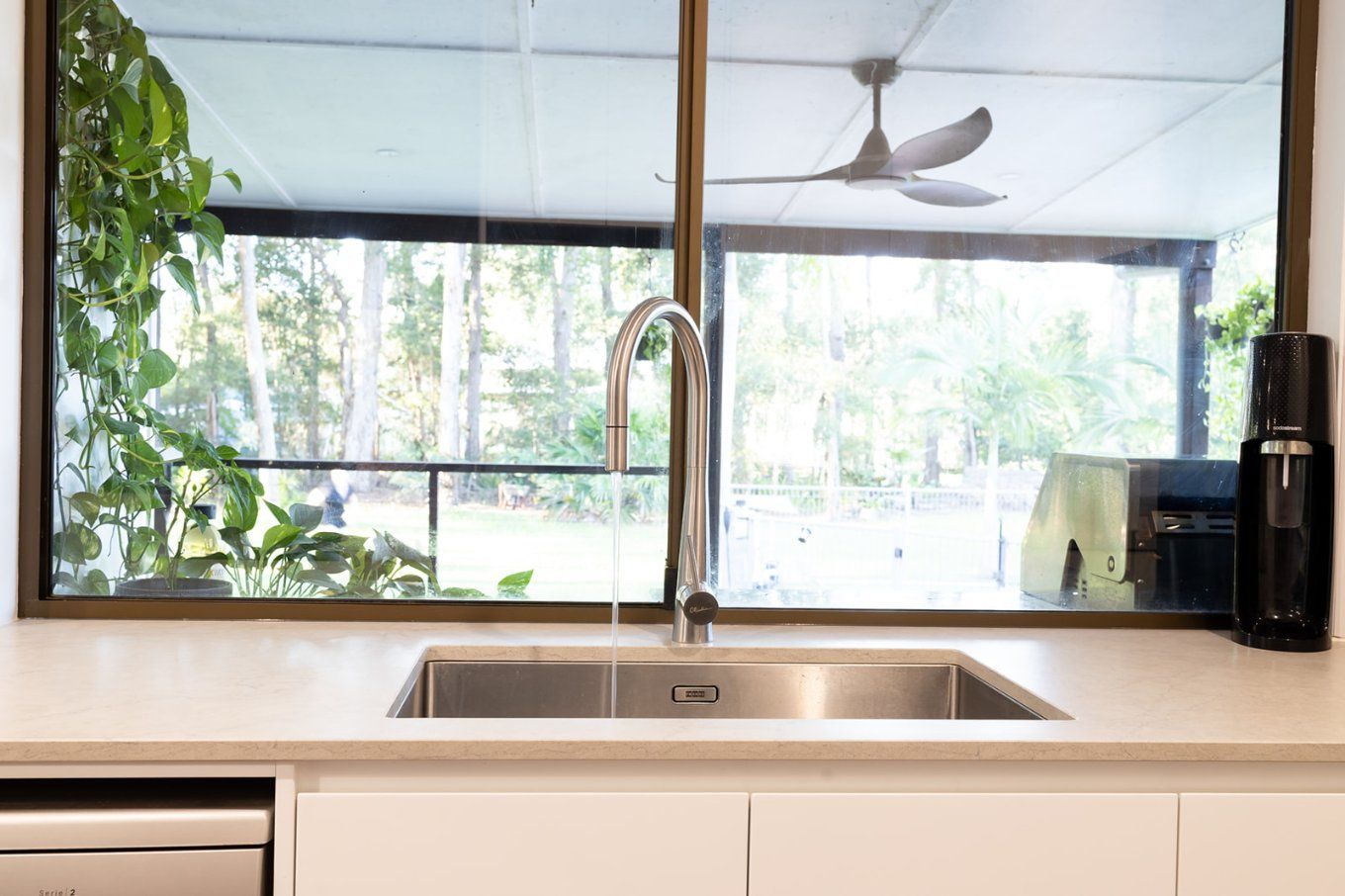 Kitchen Sink With Chrome Faucet Set Against a Large Window — Truline Cabinets In Tuchekoi, QLD