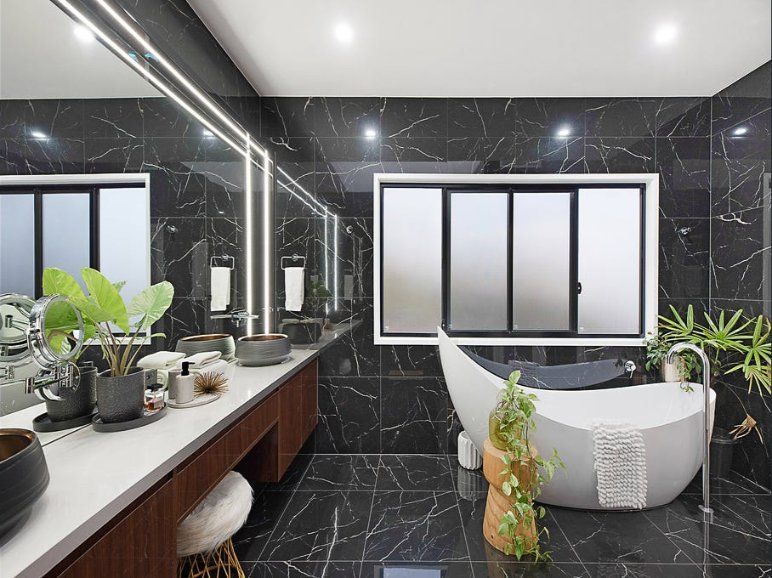 Luxurious Modern Bathroom With Black Marble Walls and a White Soaking Tub — Truline Cabinets In Tuchekoi, QLD