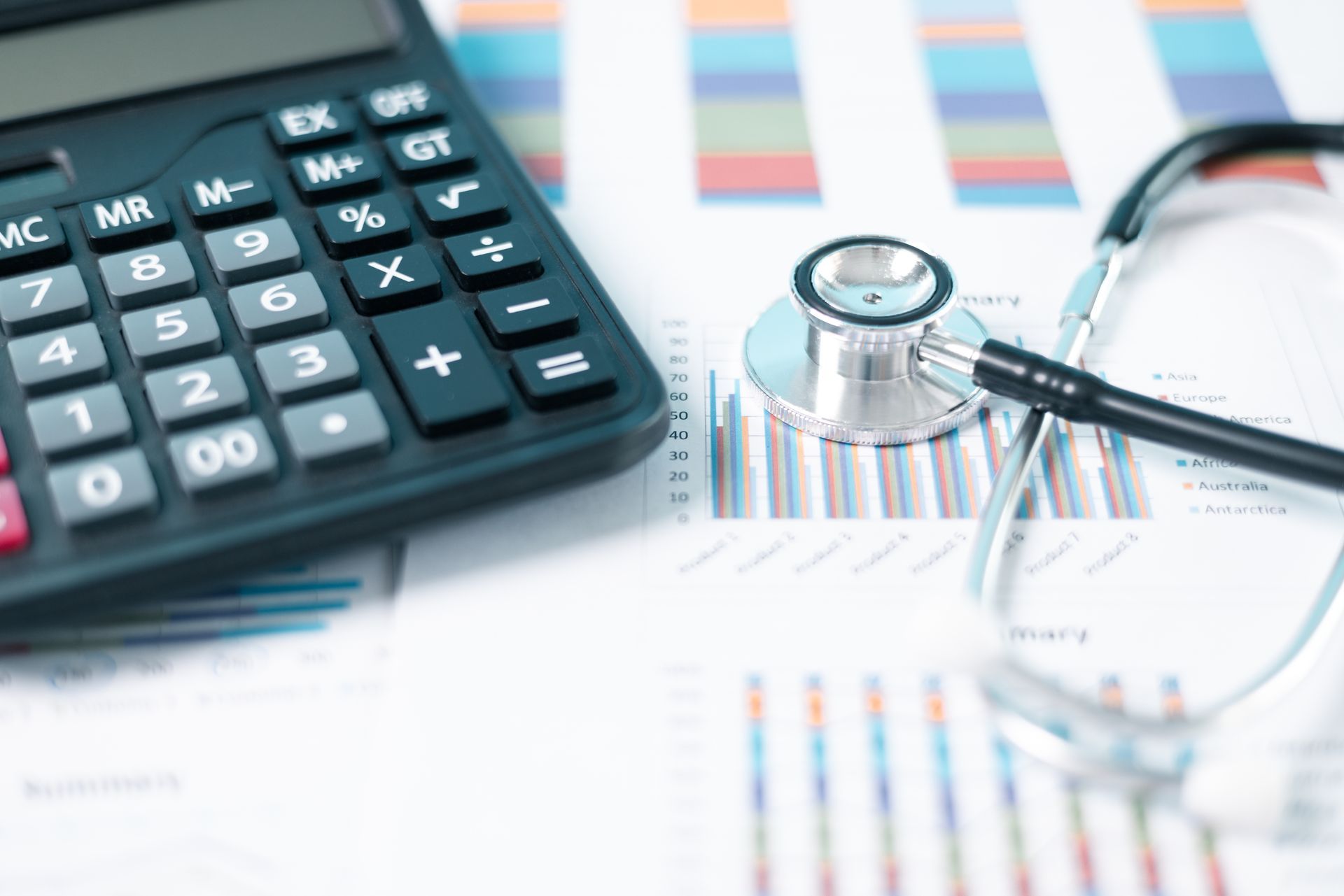 Taschenrechner und Stethoskop auf Finanzdiagrammen.