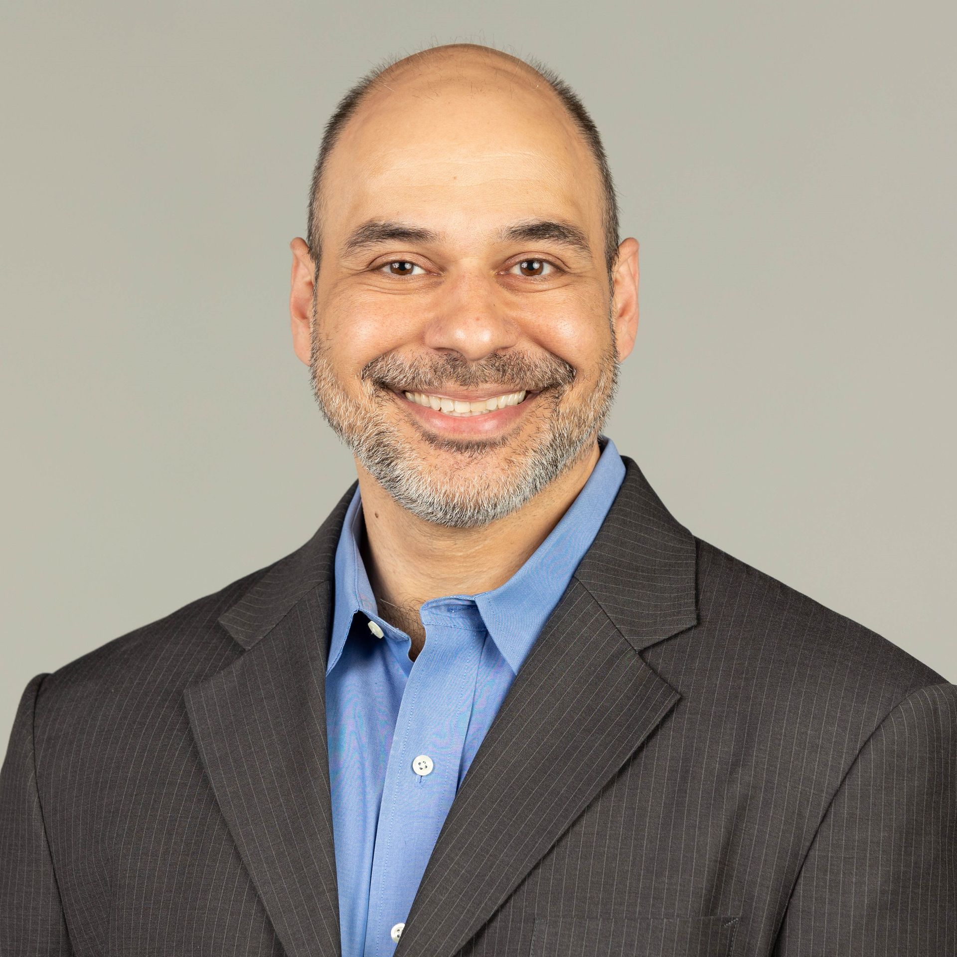A man in a suit and blue shirt is smiling for the camera.