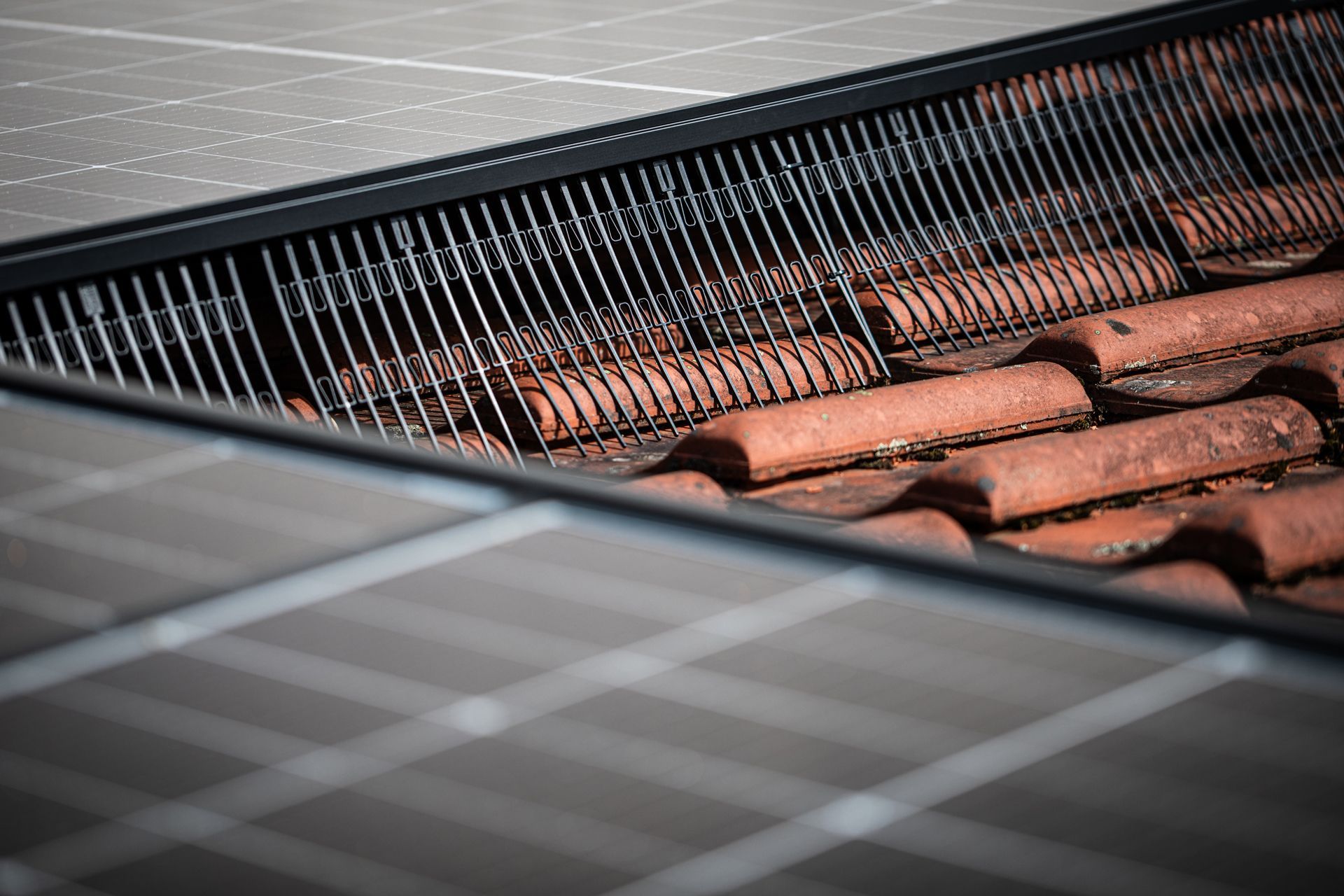 Solar panels installed on a roof with tile, next to a gutter guard.
