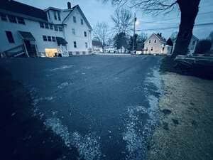 Icy residential street with houses and bare trees on a cold, overcast day