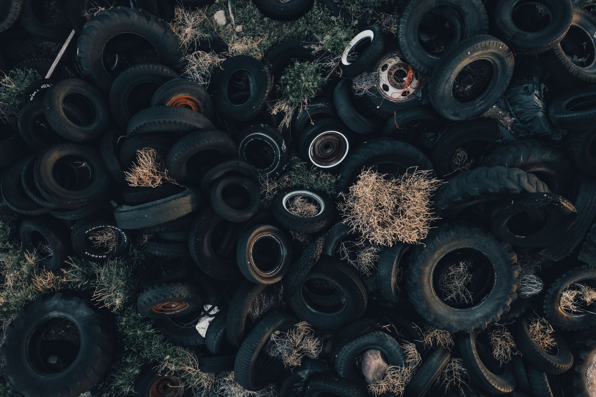 Pile of discarded black tires and debris in a dark, cluttered outdoor setting