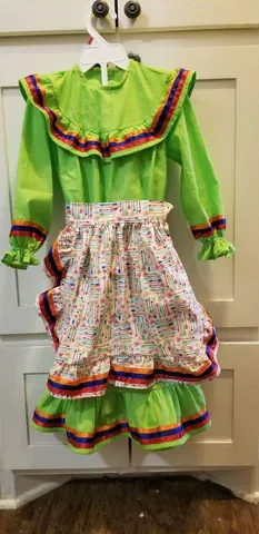 A green dress with a white skirt is hanging on a hanger.