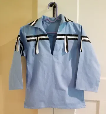 A blue shirt with black and white stripes is hanging on a hanger