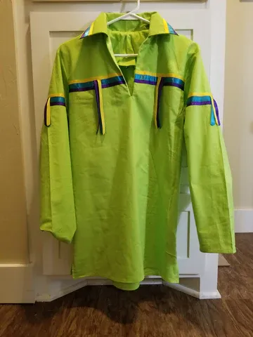 A green shirt is hanging on a hanger on a wooden floor.