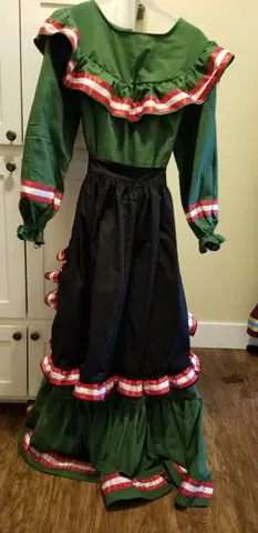 A green and black dress is hanging on a hanger on a wooden floor.
