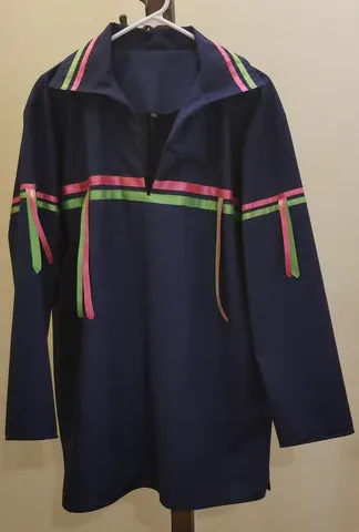 A blue shirt with pink green and yellow stripes is hanging on a hanger.