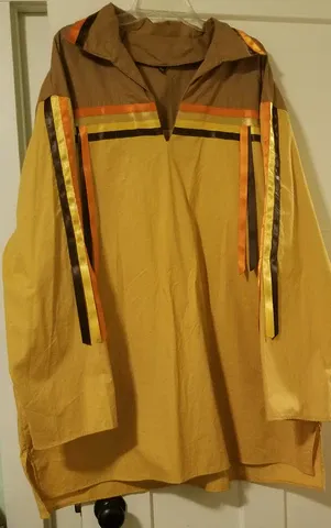 A yellow and brown shirt with ribbons on the sleeves is hanging on a hanger.