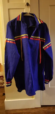 A blue shirt is hanging on a hanger in a closet.