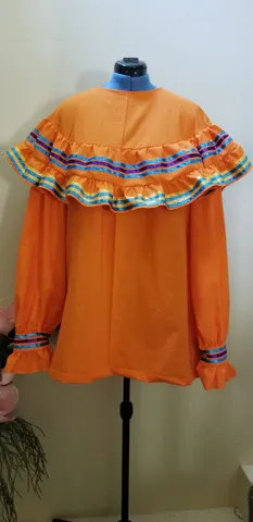 A mannequin is wearing an orange dress with ruffles on the sleeves.