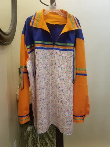 A colorful jacket is hanging on a hanger in front of a mirror.