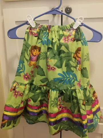 A green childs  skirt is hanging on a blue hanger.