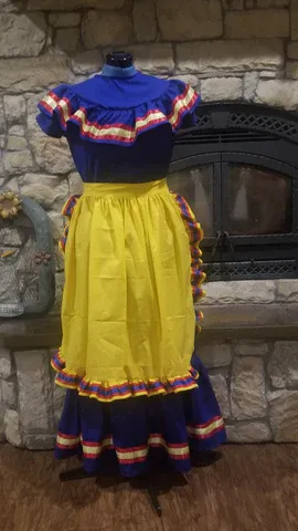 A blue and yellow dress is on a mannequin in front of a fireplace.