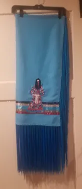 A blue scarf with fringe is hanging on a hanger.