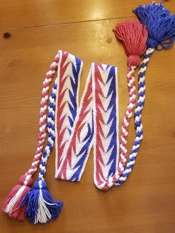 A red white and blue sash with tassels on a wooden table