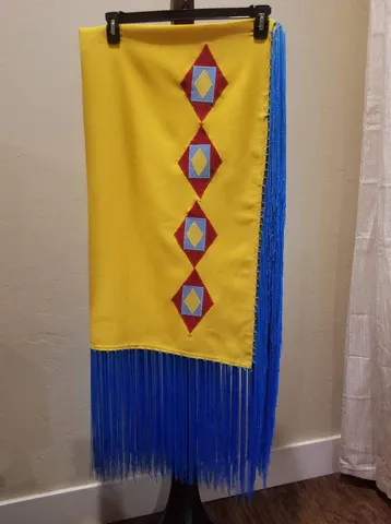 A yellow scarf with blue fringe is hanging on a hanger.