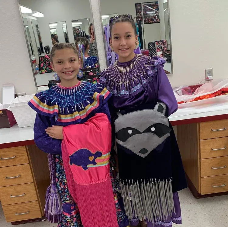 Two young girls in native american costumes are posing for a picture