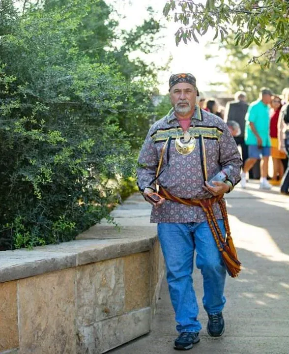A man in a native american outfit is walking down a sidewalk