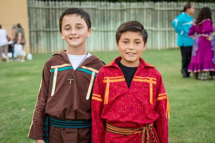 Two young boys in native american costumes are posing for a picture.