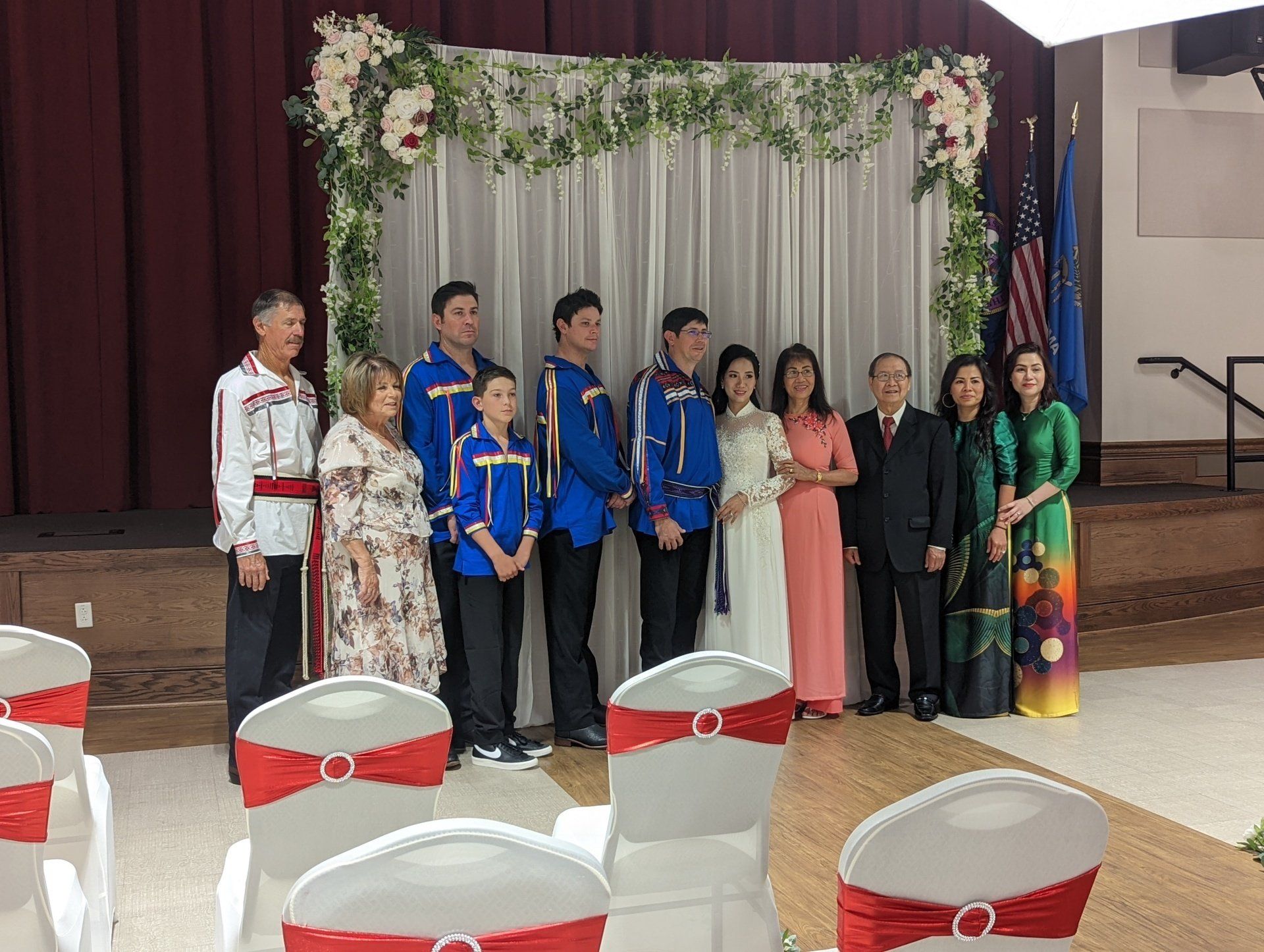 Wedding collection, people are posing for a picture in front of a stage.