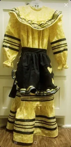 A yellow dress with black stripes and a black skirt is hanging on a hanger.