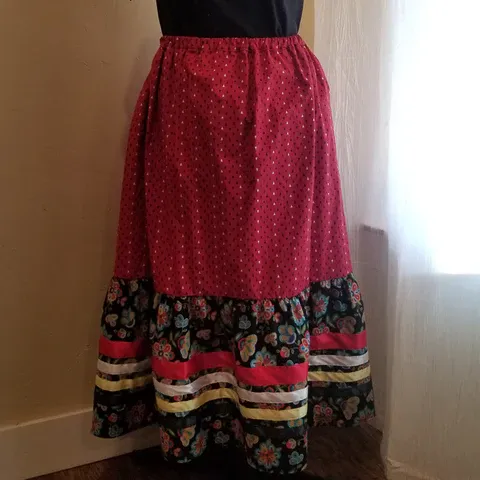 A red and black skirt is on a mannequin in front of a window.