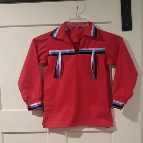 A red shirt is hanging on a white door