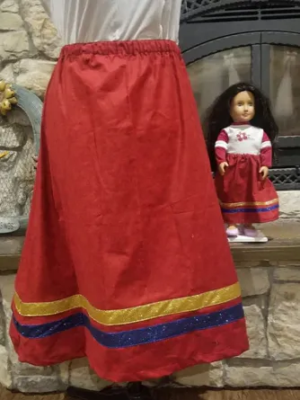 A woman wearing a red skirt is standing next to a doll