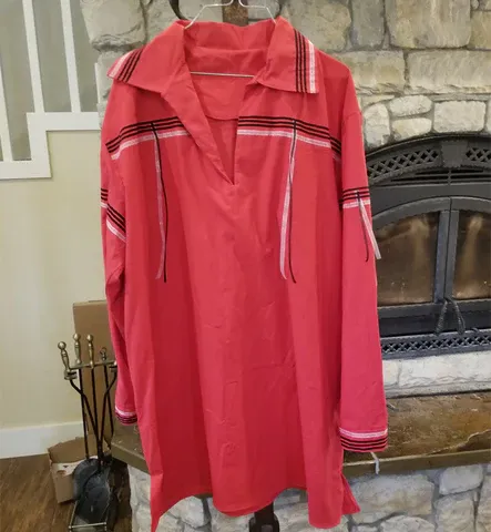 A red shirt is hanging on a hanger in front of a fireplace
