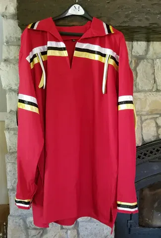A red shirt is hanging on a hanger in front of a fireplace.