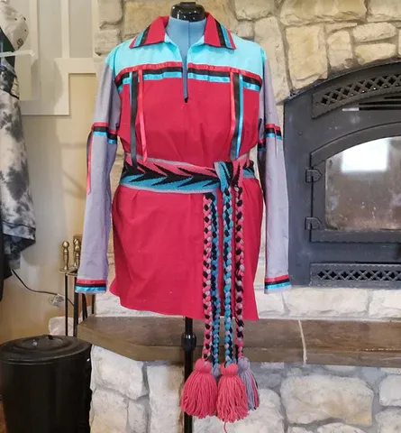 A red and blue dress is on a mannequin in front of a fireplace