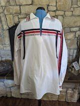 A white shirt with red and black stripes is on a mannequin in front of a stone wall.