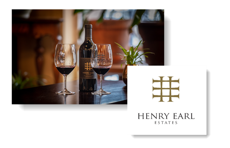 A bottle of wine sits on a table next to two glasses of wine.