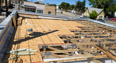 Rooftop under construction with exposed wood framing and OSB sheathing on a sunny day