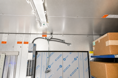 Industrial ceiling with exposed wiring, wall panels, and stacked cardboard boxes in a storage area