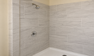 Gray tiled shower corner with chrome showerhead and control valve