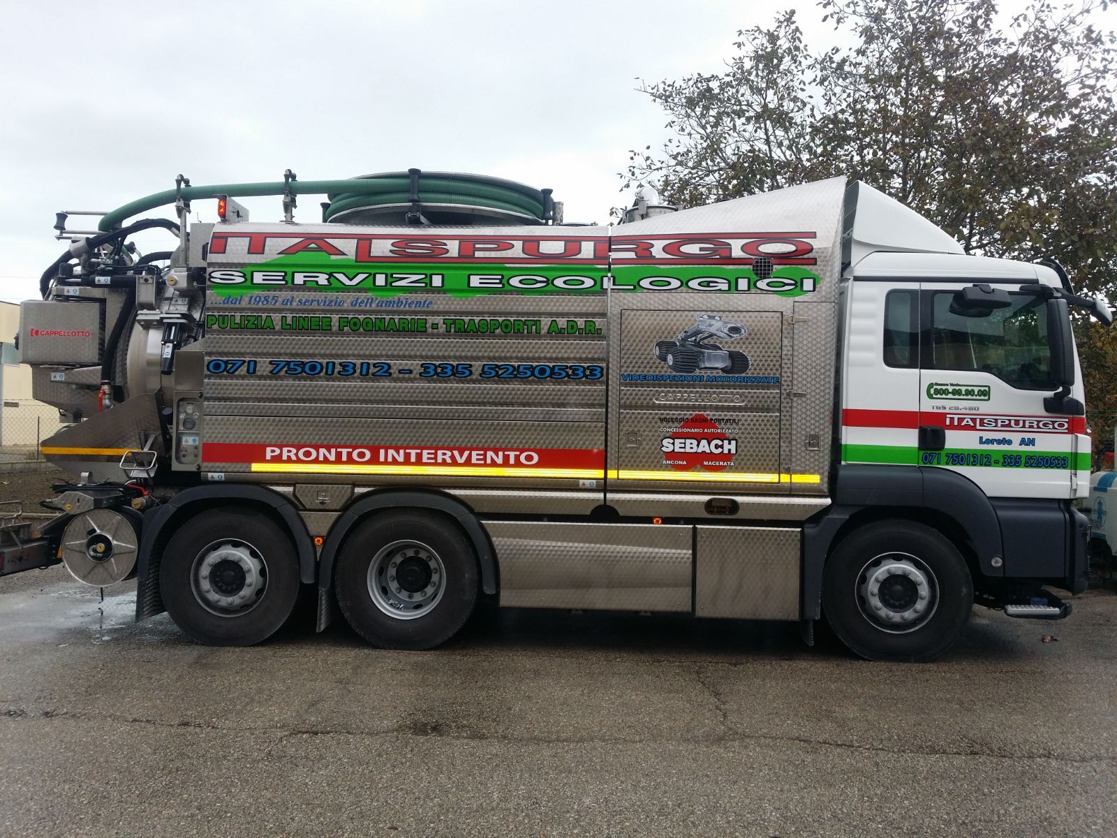 Camion di servizio decorato parcheggiato su una strada bagnata, vista laterale con attrezzature colorate e portatubi