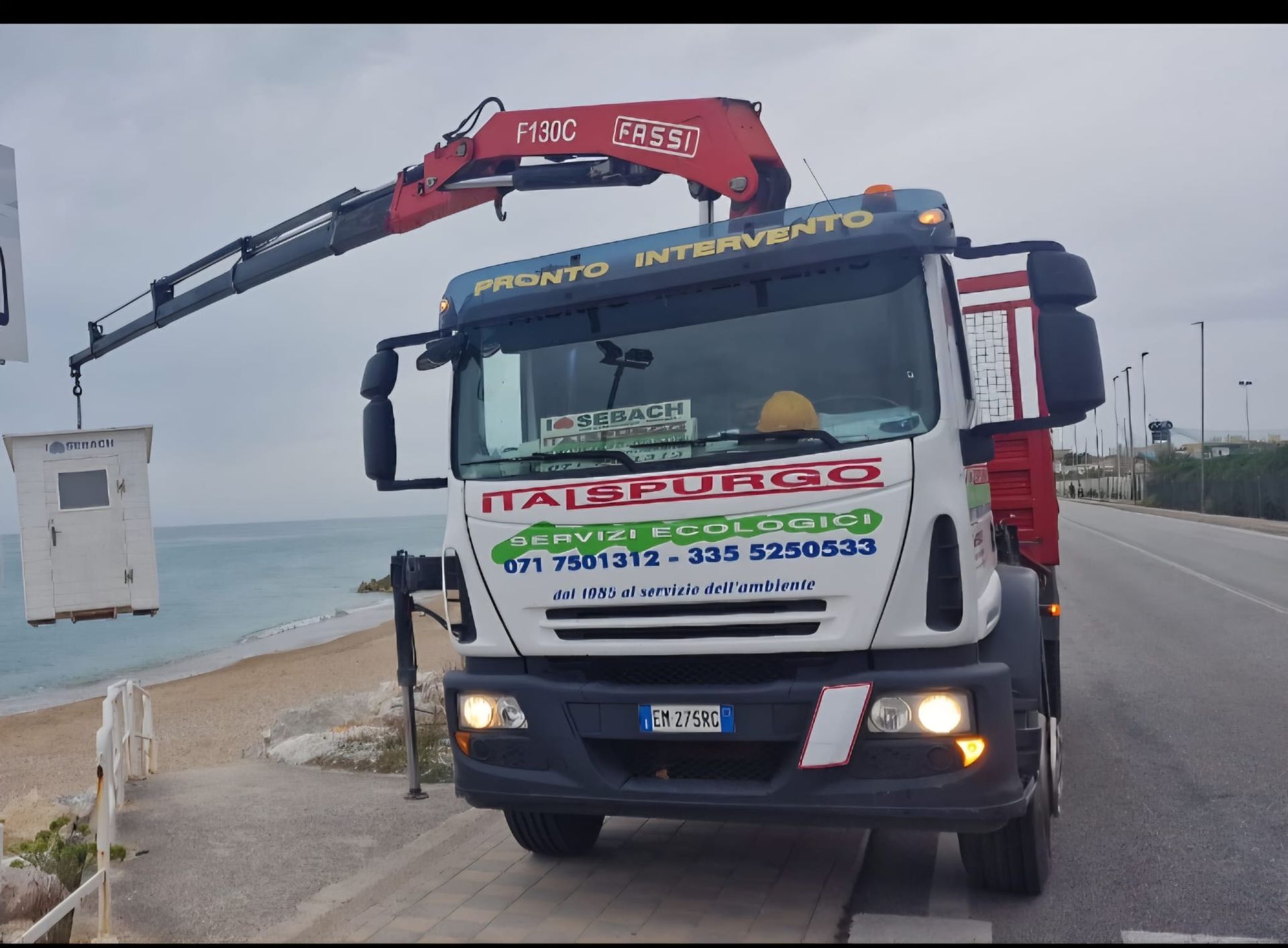 Camion di servizio bianco e verde parcheggiato su una strada bagnata, vista frontale