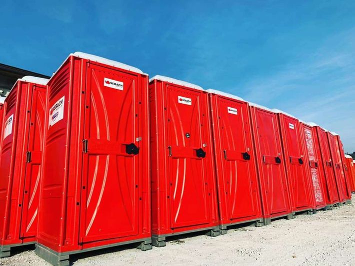 Una fila di bagni portatili rosso acceso allineati all'aperto sotto un cielo azzurro