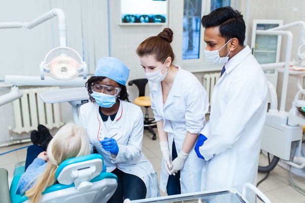 Dental professionals provide collaborative patient care in a clinical environment. Dental professionals provide collaborative patient care in a clinical environment.