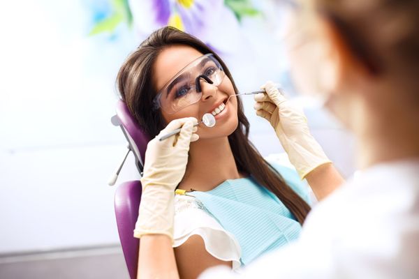 A woman at the dentist getting her teeth checked.