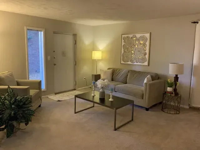 Living room with beige furniture, a modern coffee table, and artwork.