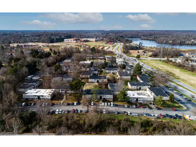 Aerial view of a suburban neighborhood with houses, trees, roads, and a river in the distance
