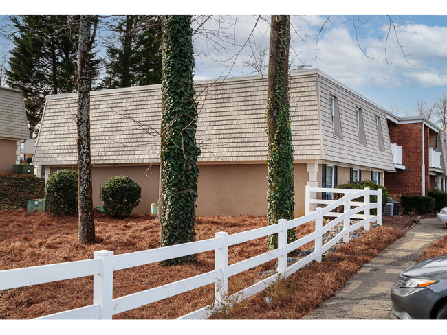 Suburban house with white fence, leafless trees, and a driveway on an overcast day