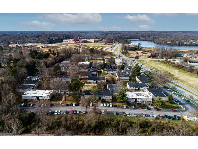 Aerial view of a residential neighborhood with apartment buildings, roads, trees, and a river in the distance.