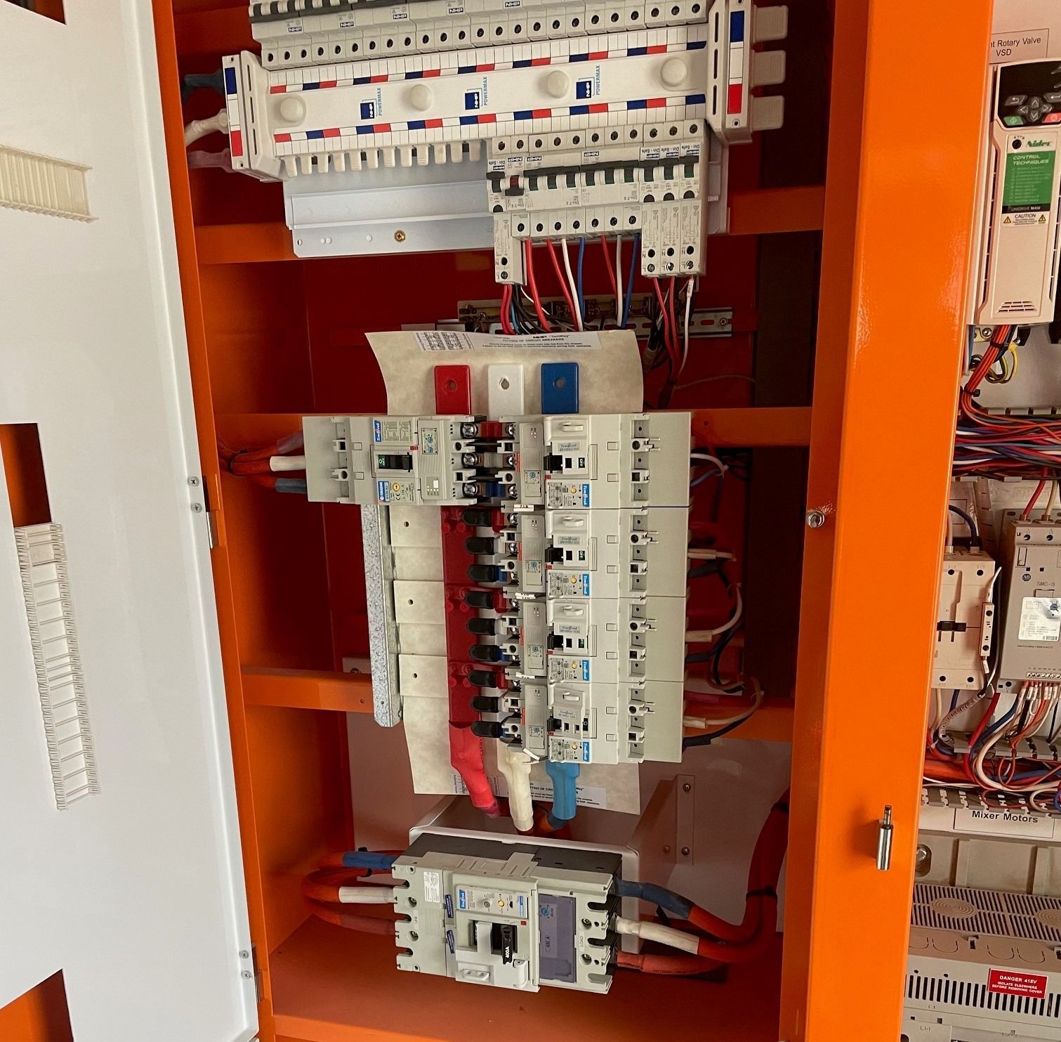 An interior view of a bright orange electrical panel with multiple circuit breakers and colored wiring.