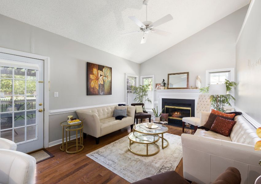 The living room of a HOA home is pictured with cream couches, dark wood floors and modern home decor.
